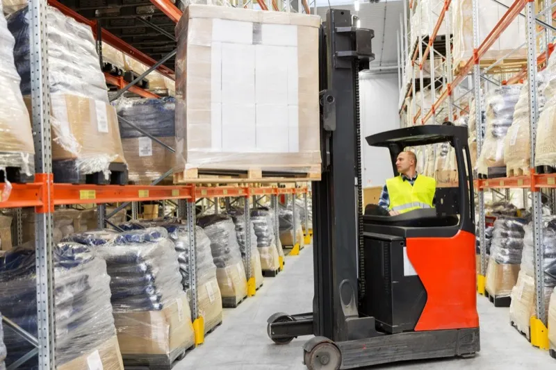 Warehouse worker inspecting lifting equipment, following LOLER regulations.