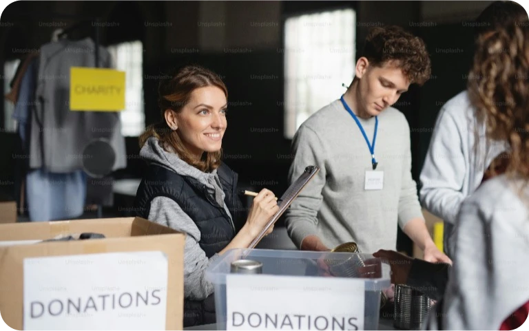 A group of volunteers working in community charity donation center, sorting out clothes and canned food.