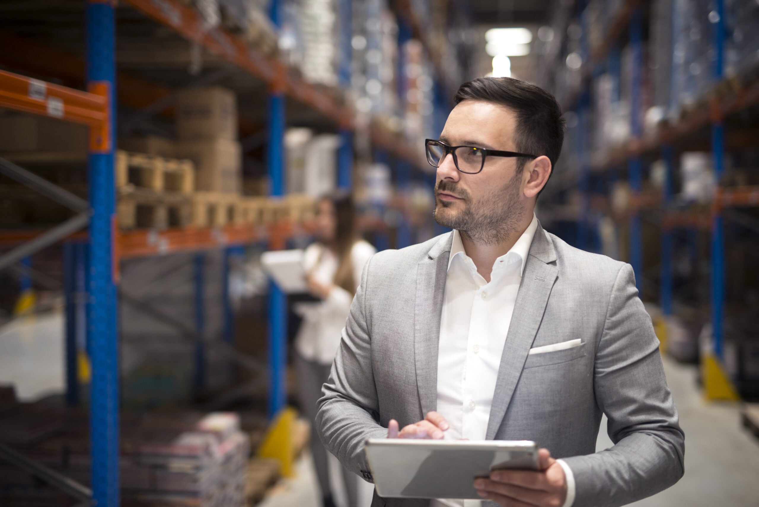 Portrait of successful businessman manager CEO holding tablet and walking through warehouse storage area looking towards shelves. How to Keep Track of Inventory for Small Business