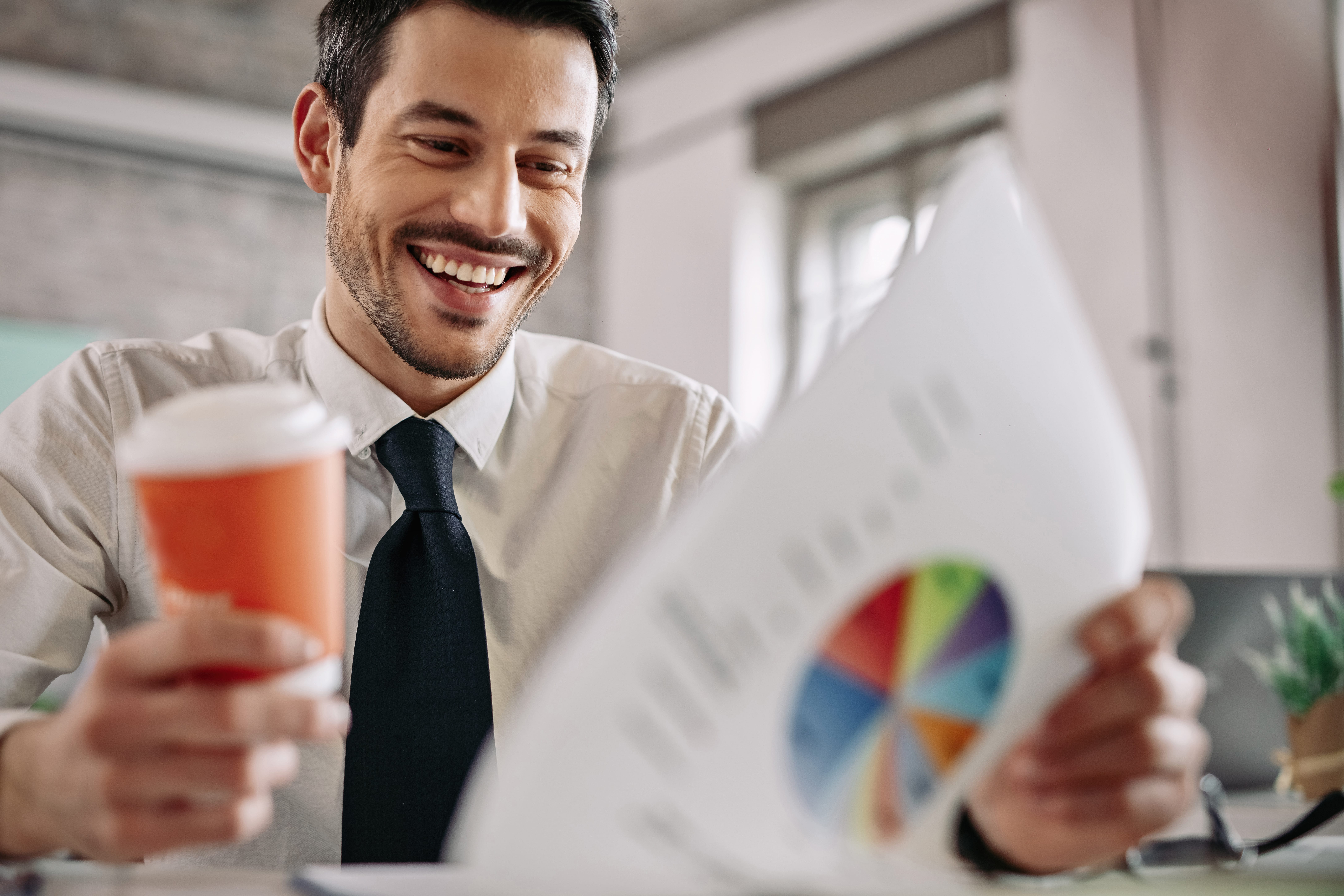 Happy businessman feeling satisfied while reading business reports at work.
